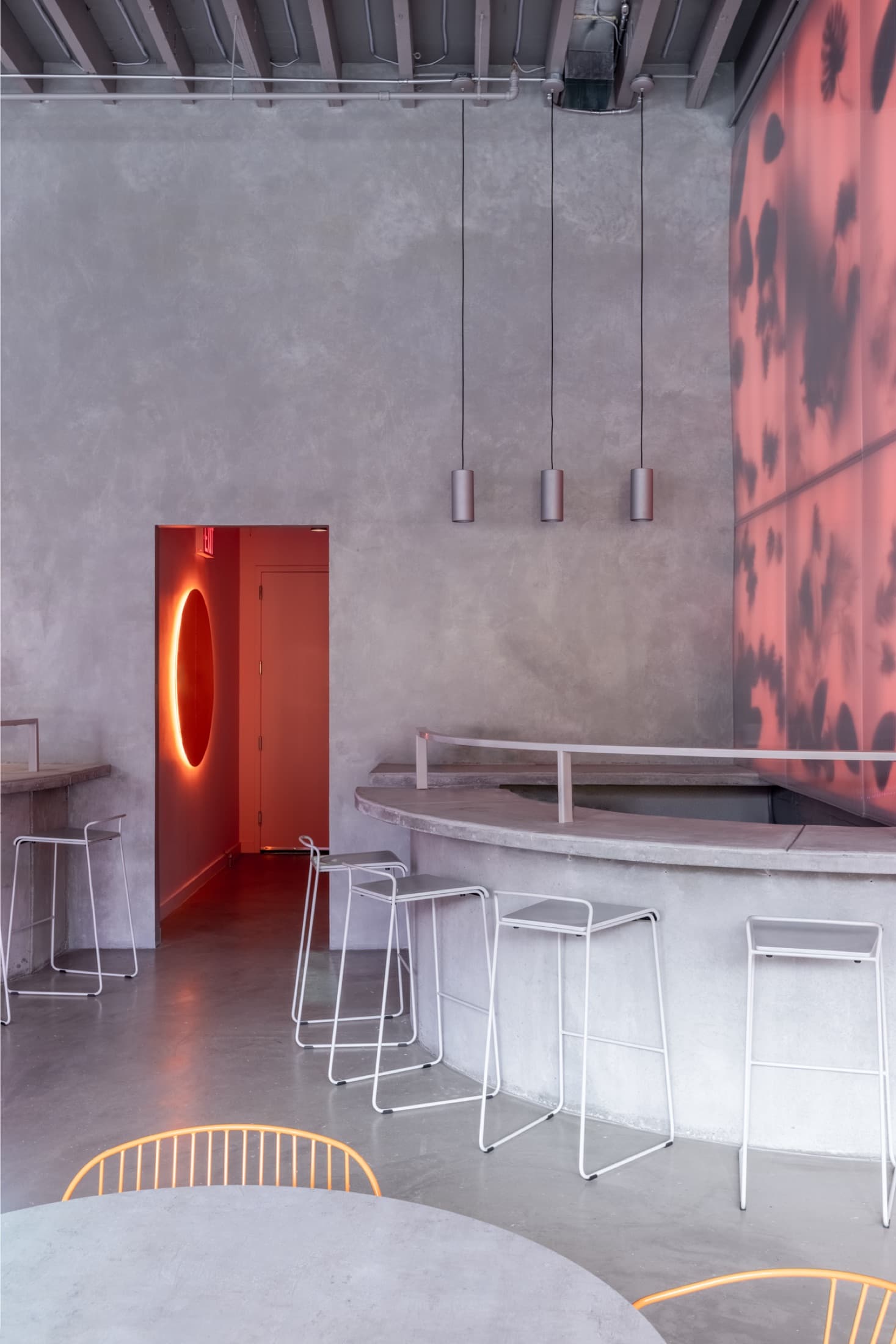 Concrete bar with pendant lights and neon oval door frame
