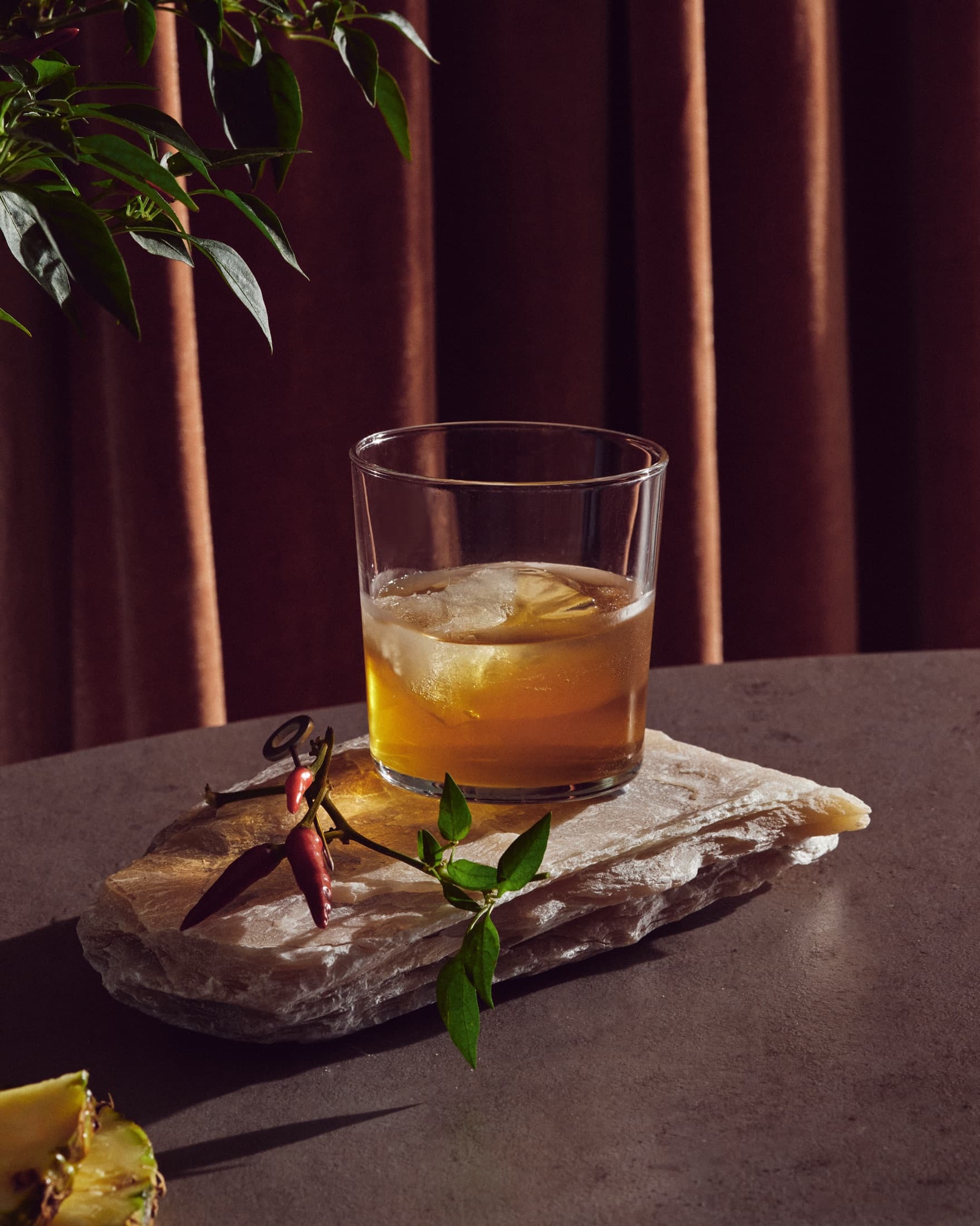 Pineapple Sling on stone slab with chili garnish